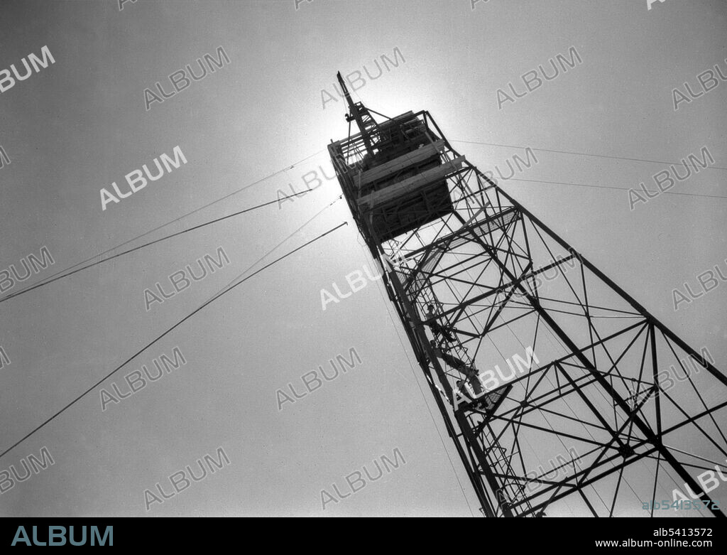 The Gadget was hoisted to the top of a 100 foot steel tower. The height would give a better indication of how the weapon would behave when dropped from a bomber, as detonation in the air would maximize the amount of energy applied directly to the target (as the explosion expanded in a spherical shape) and would generate less nuclear fallout. The tower stood on four legs that went 20 feet into the ground, with concrete footings. Atop it was an oak platform, and a shack made of corrugated iron that was open on the western side. The Gadget was hauled up with an electric winch. A truckload of mattresses was placed underneath in case the cable broke and the Gadget fell. The seven man arming party, consisting of Bainbridge, Kistiakowsky, Joseph McKibben and four soldiers including Lieutenant Bush, drove out to the tower to perform the final arming shortly after 22:00 on July 15.  The Manhattan Project was a research and development program by the US with the UK and Canada that produced the first atomic bomb during WWII.