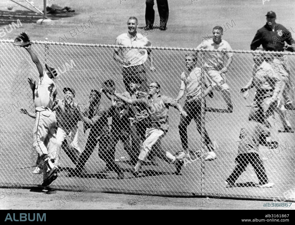 San Francisco, California: August 6, 1961. Milwaukee Braves' Hank Aaron goes to try and catch a home run ball hit by Matty Alou of the San Francisco Giants. He gets plenty of backing from the bleacherites at Candlestick Park.