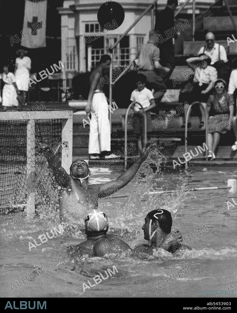 Olympics - Water Polo - Italy Beats Australia : P. Buonocore, Italian Goalkeeper in the Olympic water Polo Team, makes a save during attack by Australia in their match at the open air pool, Finchley, London, today July 30. Australian attacker (White cap) is Jack Ferguson. Italian Defender (Dark Cap No. 2) is N. Bulgarelli. Italy won 9-0. July 30, 1948. (Photo by Olympic Photo Association).