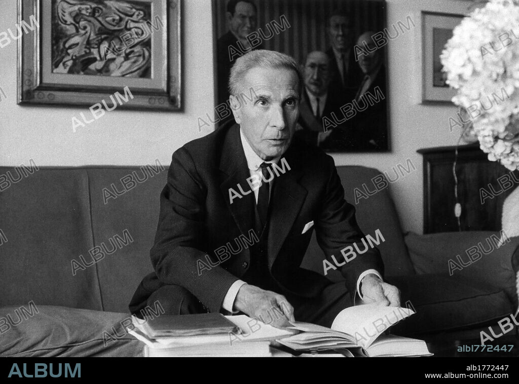 Dino Buzzati at home. Dino Buzzati, Italian writer, journalist and painter, sitting on a couch at home. Milan, 1971.