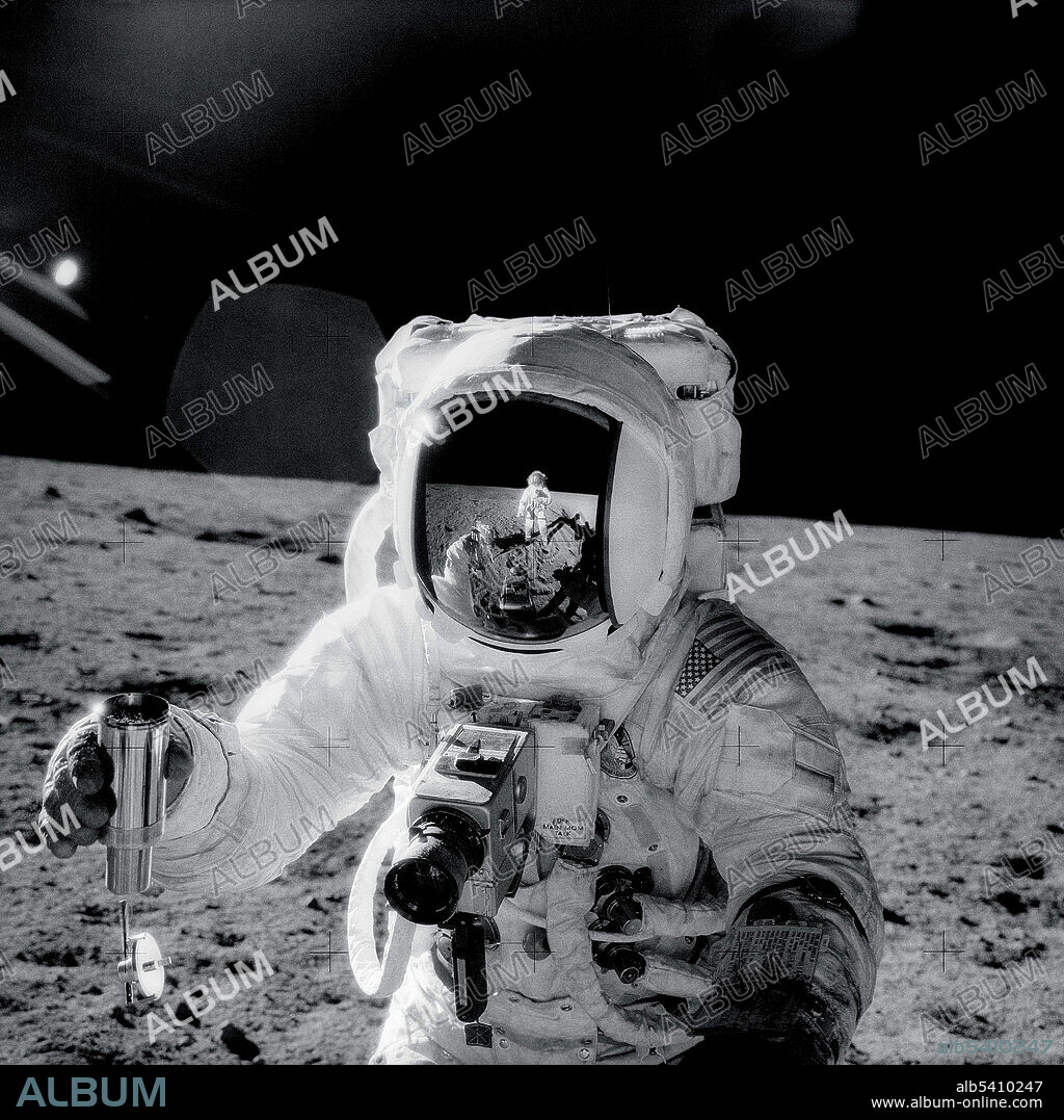 Apollo 12 astronaut Alan Bean holds an environmental sample container filled with lunar soil collected during his walk on the lunar surface on November 20, 1969. A Hasselblad camera is mounted on the chest of his spacesuit. Pete Conrad, who took this image, is reflected in Bean's helmet visor.