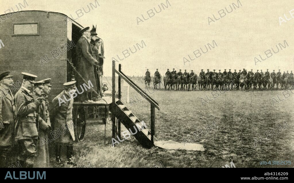 Queen Mary of Teck visits soldiers at Aldershot in Hampshire, First World War, 1915, (c1920). 'The Queen doing Duty for the King after His Majesty's Accident: a royal review of troops in training at Aldershot. The Queen was accompanied on this occasion by Princess Mary and Prince Albert. A motor lorry was used as a saluting base.' Irish cavalry are marching past. King George V was unable to attend this occasion, having been injured in a fall from his horse while visiting troops on the French front. From "The Great World War - A History" Volume IV, edited by Frank A Mumby. [The Gresham Publishing Company Ltd, London, c1920].