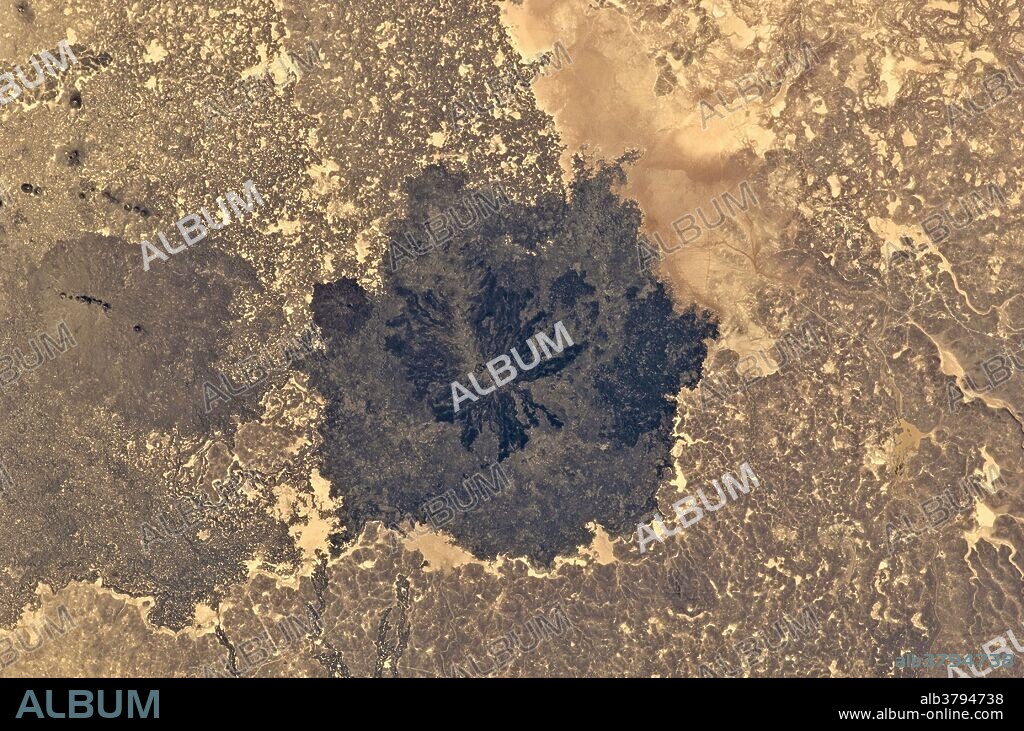 View from space of Es Safa, a striking basaltic volcano field located to the southeast of Damascus, Syria. The most recent activity was a boiling lava lake observed in the area around 1850, which appears as a dark stain in the image, over the older, lighter colored flows.