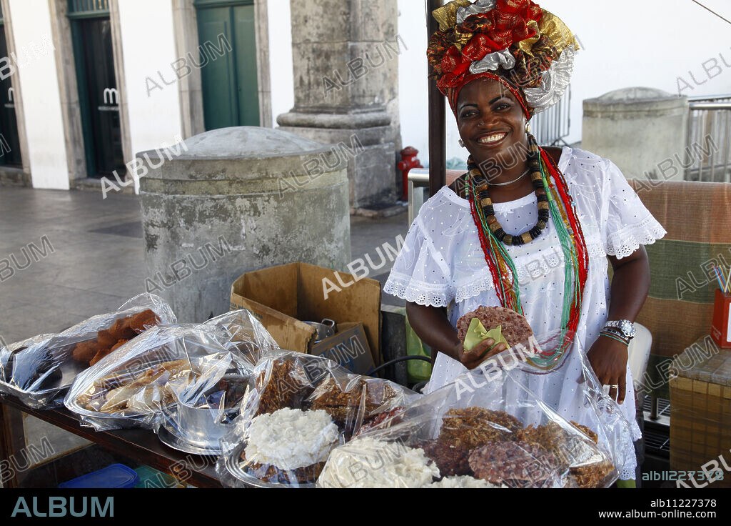 Bahian woman in traditional white dress (Baiana) selling street food at the Pelourinho district, Salvador (Salvador de Bahia), Bahia, Brazil, South America.