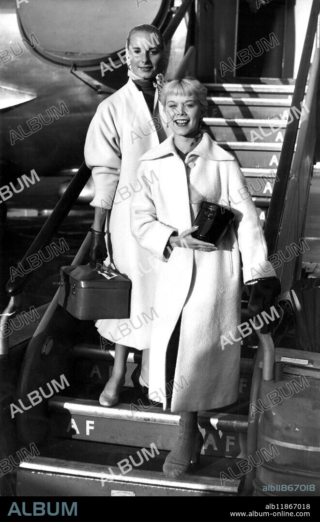 Model Zoe Newton , 18 , the " Milk Girl " whose smiling face on advertisements has made her familiar to millions , has now been chosen to play a cigarette girl at a Berlin nightclub in the film ' I Am a Camera ' . Here she steps from from an Air France liner at London Airport . But covering her left foot is a protective sock - she fears she has a badly sprained ankle . Accompanying Zoe is actress Eliette Mouret . The girls had flown over from Paris after filming there . Miss Newton is one of Britain's most photographed cover girls and her face is seen by thousands of people on ' drink more milk ' posters . 13 November 1954.