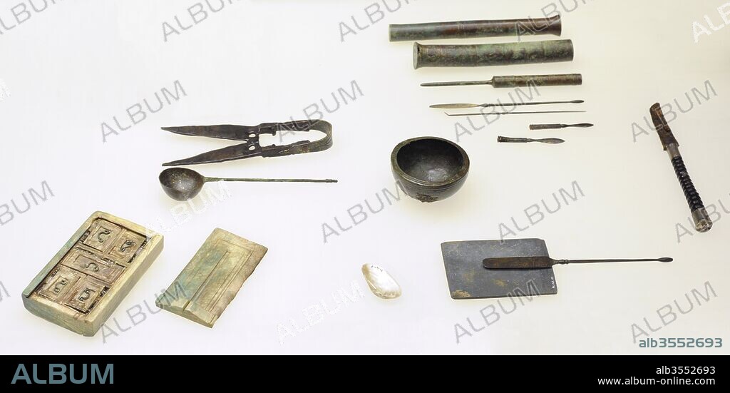 Ajuar funerario de un médico romano: dos escalpelos, tres sondas con bronce, un catéter, botiquín de marfil, paleta de pizarra para moler ingredientes para ungüentos, cuenco de bronce para mezclar medicinas, tijeras de metal (bronce y hierro), cuchillo de hierro, cuchara de bronce con marcas en el mango para la medición de líquidos, dos amuletos de plata con hechizos grabados, que indican que el médico creía también en la magia además de en la ciencia. Mediados del siglo III. Museo Romano-Germánico. Colonia. Alemania.