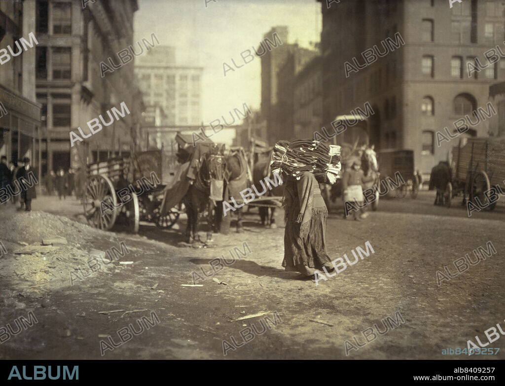 Woman carrying heavy load of clothes on her shoulders, Lafayette Street below Astor Place, New York City, New York, USA, Lewis Wickes Hine, National Child Labor Committee Collection, February 1912.