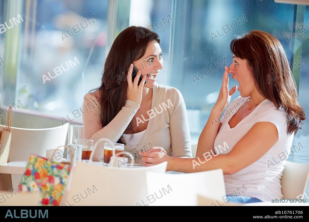 Speaking by phone. Women sisters 35 and 40 years taking coffee on a terrace. Donostia. San Sebastian. Gipuzkoa. Basque Country- Spain.