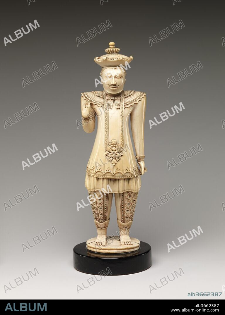 Portrait of the Sinhalese King Sri Vikrama Raja Sinha (r. 1798-1815). Culture: Sri Lanka, Kandy district. Dimensions: H. 9 in. (22.9 cm); W. 3 in. (7.6 cm); D. 2 3/8 in. (6 cm). Date: early 19th century.
This portrait of the last Kandyan king shows him displaying his regalia: the six-pointed crown, a long shirt (kamisiya), a tunic (bo-hettya), and a cape (mante), over which hangs a floral pendant. The hand gestures mimic those of the Buddha: one raised, the other lowered and holding the robe. Such portraits are rare and were probably produced as presentation gifts for visiting diplomats.