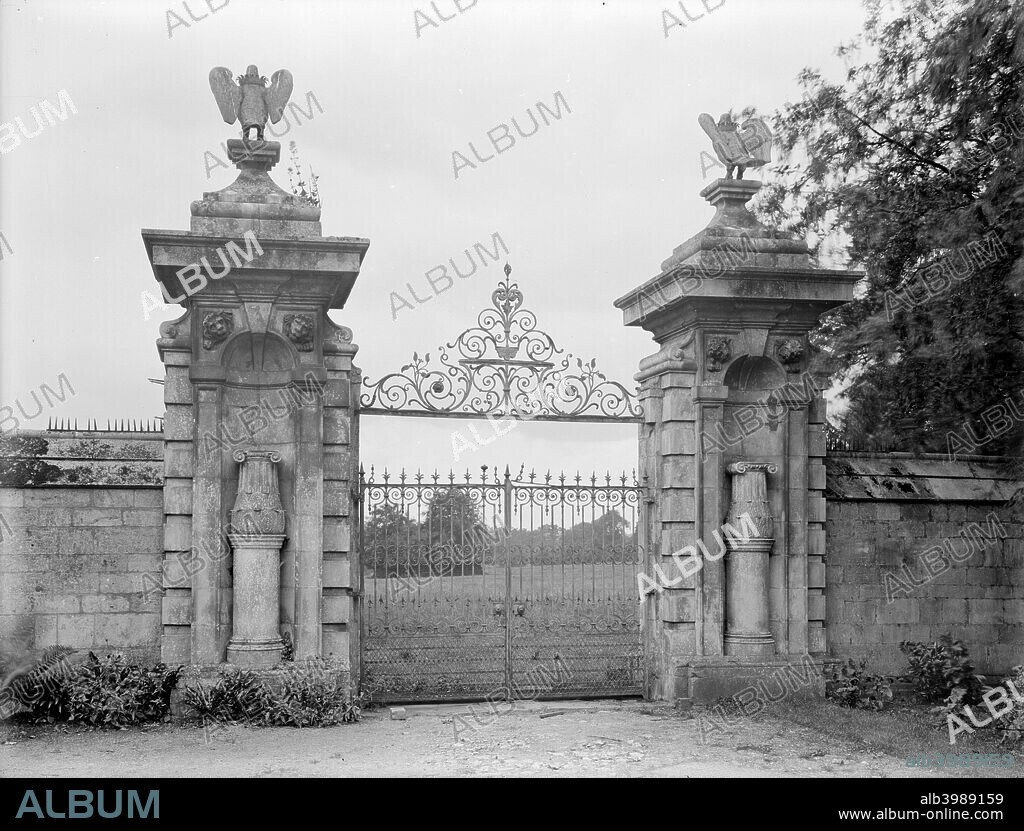 Gateway at Thorpe Hall, Longthorpe, Peterborough, Cambridgeshire, 1928. The south gateway to the walled garden at Thorpe Hall. Eagles surmount the posts, and the niches on the gate piers are filled with vases, crowned with Ionic capitals on pedestals, an example of Mannerist ornament typical of the period when the Hall was built, c1653-6. The wrought iron gates have seen better days, and weeds grow from the stonework.