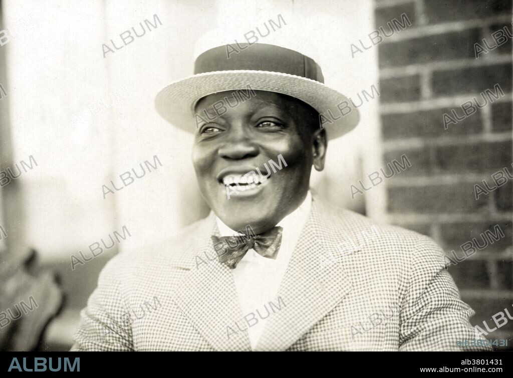 John Arthur "Jack" Johnson (March 31, 1878 - June 10, 1946) was the first African-American world heavyweight boxing champion (1908-15). He had a unique fighting style, which was not customary to boxing during this time. He would fight defensively, waiting for his opponents to tire out. He would continuously dodge their punches, and quickly strike back with a blow of his own. He often made his fights look effortless, but when pushed he could also display some powerful moves, and punches. He was an early example of the celebrity athlete in the modern era, appearing regularly in the press and later on radio and in motion pictures. On June 10, 1946, he died in a car crash after racing angrily from a diner that refused to serve him. He was 68 years old. During his boxing career, he fought 114 fights, winning 80 matches, 45 by knockouts. He was inducted into the Boxing Hall of Fame in 1954, and is on the roster of both the International Boxing Hall of Fame and the World Boxing Hall of Fame. Underwood & Underwood photograph inscribed "Jack is to defend his crown of worlds heavyweight championship in a bout with James "Tut" Jackson on July 4, 1922 at Washington Courthouse, Ohio.".