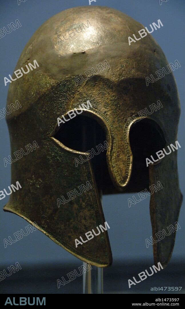 ARTE GRIEGO. YELMO o CASCO DE BRONCE de tipo corintio. Ofrenda votiva en el Santuario de Zeus por Hieron, tirano de Siracusa, y sus seguidores después de la victoria en Cyme (Italia) contra los etruscos en el año 474 a. C. Museo Arqueológico de Olimpia. Provincia de Ilía. Región del Peloponeso.