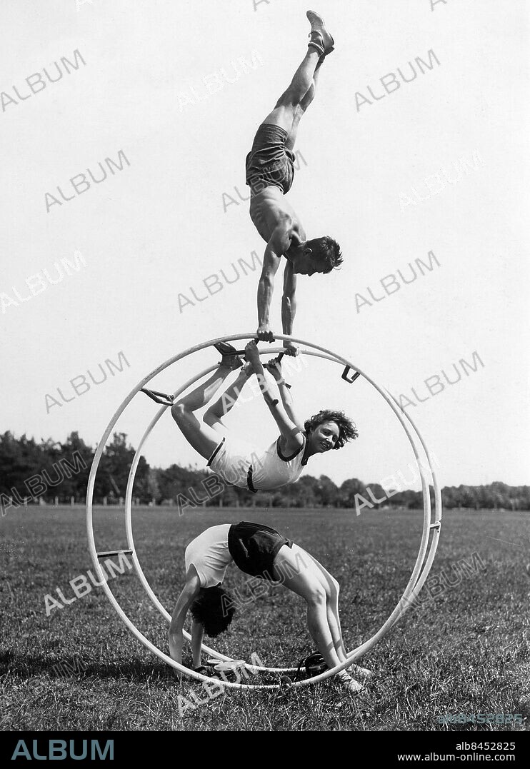 TYSKLAND BERLIN omkring 1926. Orig. bildtext... DAS RHÖNRAD ALS GYMNASTISCHES UEBUNGSGERÄT bei der Hochschule für Leibesübungen im Stadion in Berlin Grunewald! Das Rhönrad, ein neues Uebungsgerät, dient hauptsächlich zur Förderung der gymnastischen Körpererziehung und nimmt heute auf diesem Gebiete den erzten Platz ein. INTERESSANTE GYMNASTISCHE UEBUNGEN AM RHÖNRAD! Ein vorbildliche gymnastische Uebung mit Handstand am Rhönrad, ausgeführt von Mitgliedern der Hochschule für Leibesübungen. Foto: A-B-C Aktuelle-Bilder-Centrale / AB Text & Bilder / SVT / Kod: 5600 Mapp: Gymnastik Gymnastikhjulet 5530 D Några studenter på en gymnastikhögskola utför gymnastiska övningar i ett hjul på Stadion i Berlin Grünewald. Bildserier Fotoreportage Formationer Trio Akrobatiska övningar Stå på händer Balans Stämpel 1926-1927 sites: TYSKLAND;BERLIN PhotoDate:192?-??-??.