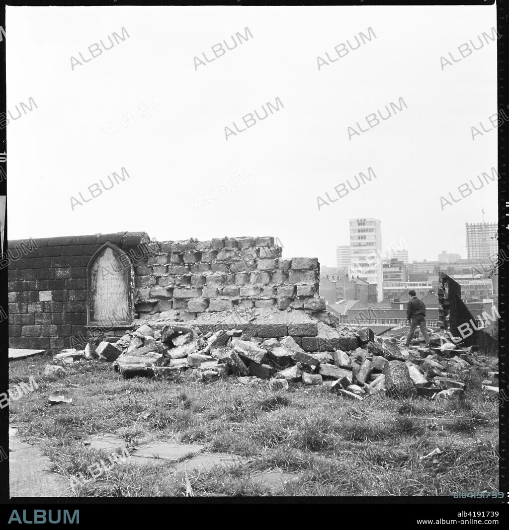 St Mary's Church, St Mary's Street, Quarry Hill, Leeds, 1966-1974. A boy walking through the demolished stonework of the the graveyard wall at St Mary's Church with buildings on Mabgate in the background and modern city centre office blocks in the distance.