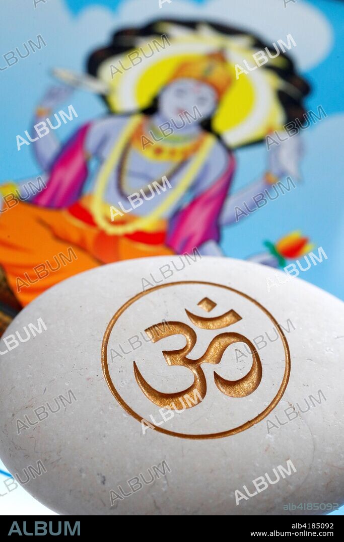The Om or Aum symbol of Hinduism and Buddhism on a white stone. Image of Vishnu on a tablet.