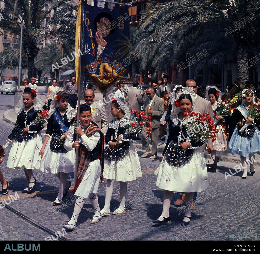 DESFILE DE NIÑAS CON FLORES PARA LA OFRENDA - FOTO AÑOS 60.