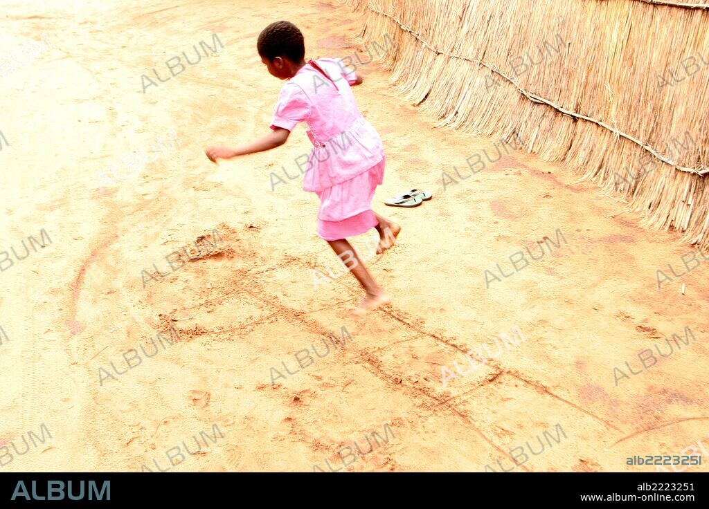A young child at Mukuni Village near Livingstone in Zambia, Africa playing Hopscotch by herself, November 2008.