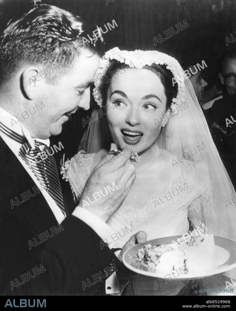 Orig. bildtext... THE GROOM OFFERS THE BRIDE SOME WEDDING CAKE Hollywood, Calif. Dr. James McNulty is shown offering his bride, the former Ann Blyth of the films, some wedding cake at a reception in Beverly Hills for an estimated 700 friends. The couple were married today in a San Fernando valley church packed with screen celebrities. The marriage rites were performed by J. Francis Cardinal McINtyre, marking the first time that a prince of the roman catholic church has solemnized a Hollywood wedding. Anm. A Blyth, f 1928, amerikansk skådespelare och sångare. Gift med J McNulty 1953. Tårtor Bakverk Gapa Smaka Blicken persons: JAMES MCNULTY;ANN BLYTH sites: HOLLYWOOD;USA.
