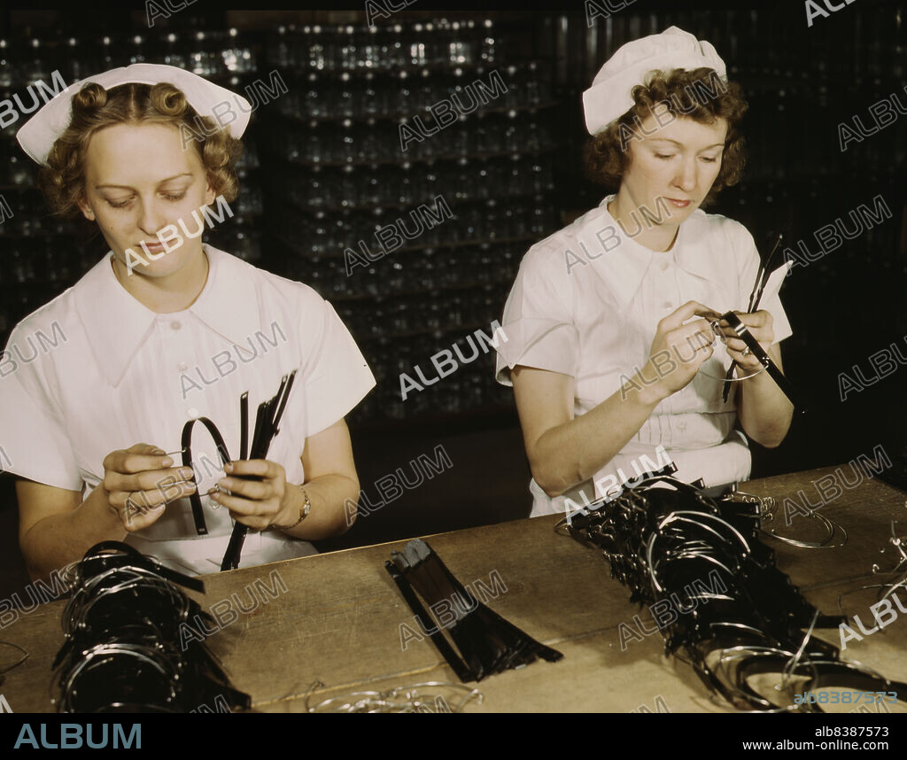 HOWARD HOLLEM. Two Navy wives, Eva Herzberg and Elve Burnham, entered war work after their husbands joined the service, Glenview, Ill. They assemble bands for blood transfusion bottles at Baxter Laboratories. Mrs. Burnham is the mother of two children.