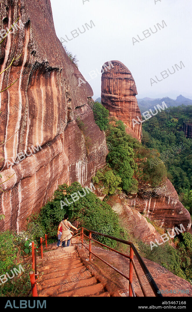Danxia Mountain meaning Red Rosy Clouds Mountain, is a famous scenic area near Shaoguan city in the northern part of Guangdong Province. The area is formed from a reddish sandstone which has been eroded over time into a series of mountains surrounded by curvaceous cliffs and many unusual rock formations (Danxia Landform). There are a number of temples located on the mountains and many scenic walks. There is also a river winding through the mountains on which boat trips can be taken to enjoy the scenery. Particularly noted are two formations: a stone pillar called the Yangyuan (male/father stone) that bears a resemblance to a phallus and the Yinyuan hole, which somewhat resembles labia.