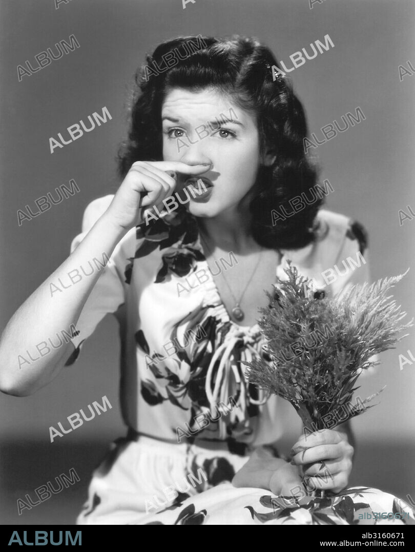 Hollywood, California: 1944 Actress Peggy Ryan tried to defuse a sneeze while holding a bouquet.