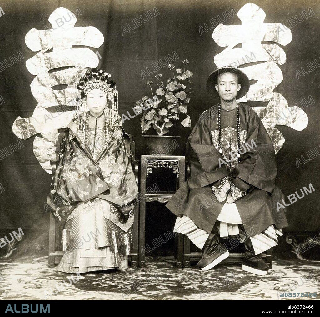 Thomas Child took a series of three photographs relating to late Qing dynasty marriage customs. This one depicts the granddaughter of General Zeng Guofan, a high-ranking Qing official, seated next to her groom.<br/><br/>. Child describes this photograph: 'Weddings are one of the stock ceremonies of the world, and every country has its own customs. In China the bridal colour is scarlet. This bride wore a scarlet satin coat embroidered with gold thread, with a skirt to match, her head dress was a mass of scarlet, gold and pearls.'.
