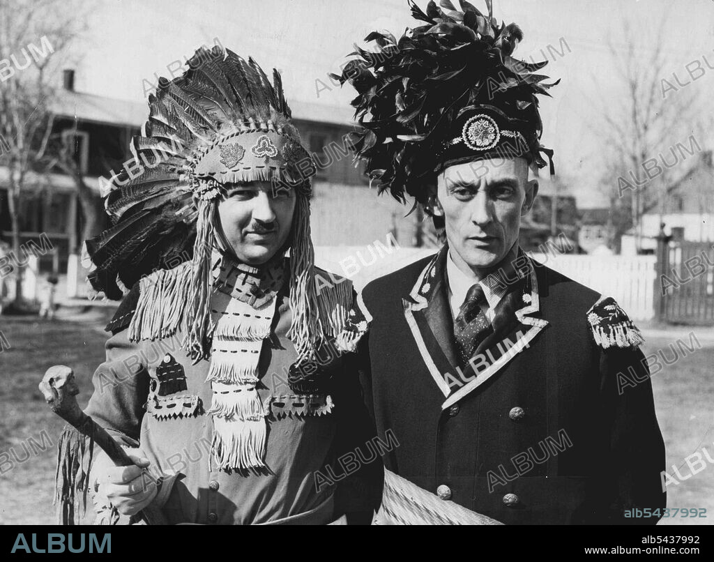 Huron Indians To Greet king And Queen -- These pictures, of the Huron Indians, the oldest tribe in North America, were made at their reservation near here, as they spruced up their ceremonial bonnets in preparation for their ceremony to greet King George and Queen Elizabeth. This close up of two Indians in war Regalia, shows Jules Sioui, (left), and Arigene Sioui. The warrior on the left is wearing the ancient Huron dress, while the brave on the right is wearing comparatively modern head-dress a.