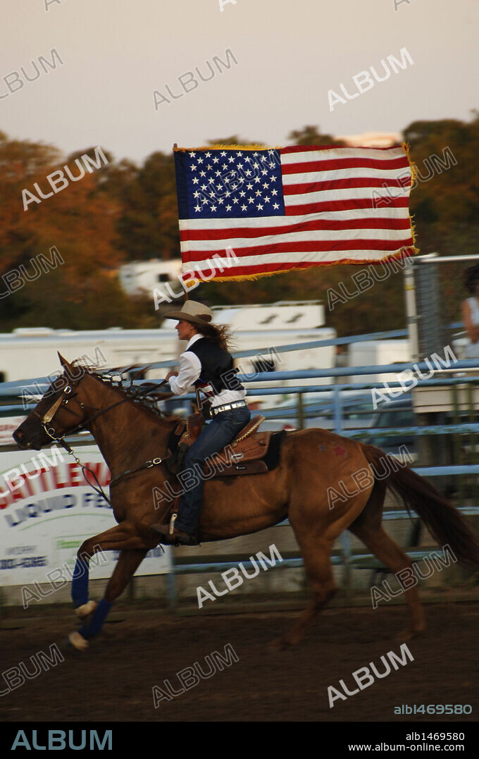 RODEO. Amazona portando la bandera estadounidense BASTROP. Estado de Texas. Estados Unidos.