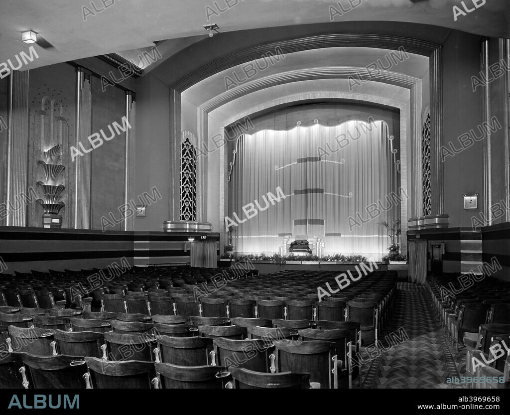 Auditorium of the Odeon, Kingston upon Thames, London, c1933, designed by Colonel James E Adamson and Marshall and Tweedy. Opened in 1933, its fittings are in Art Deco style, particularly the organ with the Odeon logo. The auditorium is empty, and the curtains are drawn, covering the screen.