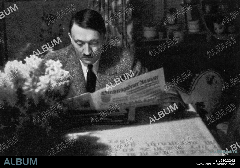 Adolf Hitler in the evening at Obersalzberg, Bavaria, Germany, 1936. Hitler (1889-1945) relaxing with the newspaper at his mountain retreat, the Berghof. A print from Adolf Hitler. Bilder aus dem Leben des Führers, Hamburg: Cigaretten/Bilderdienst Hamburg/Bahrenfeld, 1936.