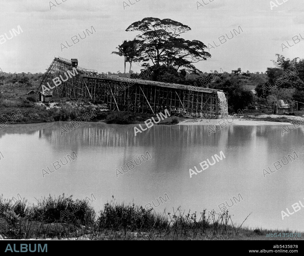 Malayan Tin - Gravel Pump And Hydraulicing - The typical Gravel pump structure viewed from the tailings area. The alluvial tin-bearing soil is washed into a pit at the other end, drawn up by suction of the gravel pump and the flow of water over the main palong washes off the lighter soils and leaves the alluvial tin deposits to be collected. July 01, 1951. (Photo by British Official Photograph).