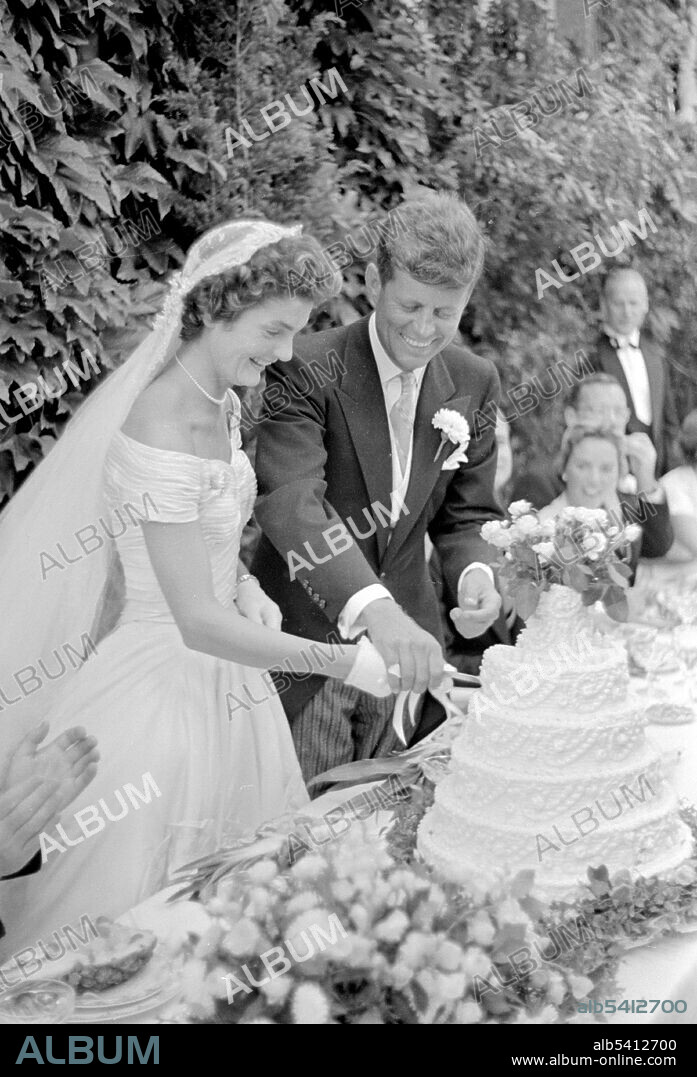 Jackie and JFK cutting their wedding cake. Jacqueline Lee Bouvier Bouvier and John Fitzgerald Kennedy married on September 12, 1953, at St. Mary's Church in Newport, Rhode Island, in a mass celebrated by Archbishop Richard Cushing. The wedding was considered the social event of the season with an estimated 700 guests at the ceremony and 1,200 at the reception that followed at Hammersmith Farm. The wedding dress, now housed in the Kennedy Library in Boston, Massachusetts, and the dresses of her attendants were created by designer Ann Lowe of New York City. Toni Frissell, 1953 (cropped and cleaned).