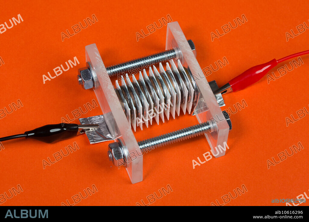 A voltaic pile battery. This type of battery was the first chemical battery and was invented by Alessandro Volta in 1791. This battery consists of two different metals. Here copper United States pennies manufactured before 1982 were used and the source of Zinc was zinc coated washers. Cotton paper is placed between the coins and wetted with an acid. In this experiment the acid used was 5 percent acetic acid from household vinegar. The vinegar is the electrolyte. Unlike the Leyden jar, the voltaic pile produces a continuous electricity and stable current. The order of the stack is copper, zinc and then paper. This pattern is repeated throughout the battery.
