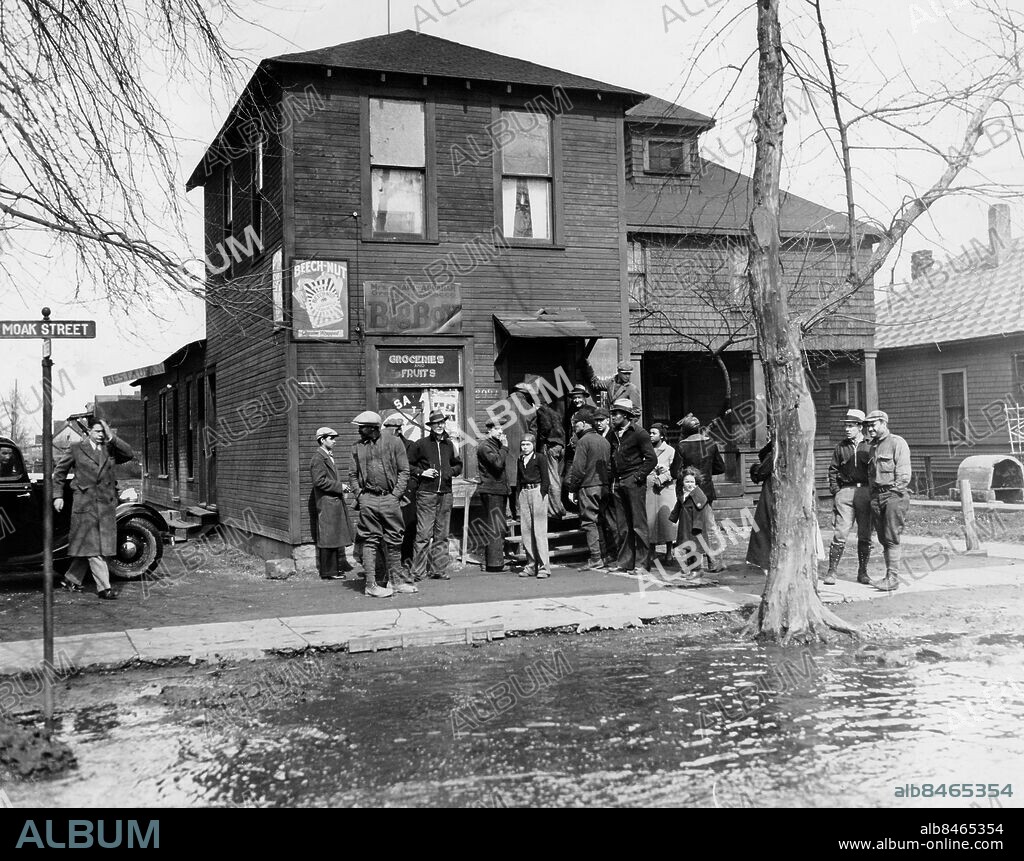 Orig. bildtext... YOUNGBLOOD KILLED IN GUN BATTLE Herbert Youngblood, partner of John Dillinger in his escape from the Crown Point, Ind. jail, a short time ago, died of bullet wounds received in a gun battle with Sheriff's officers who had trapped him in a store in Port Huron, Mich., March 16. Shown above is the store in which Youngblood was captured. Sheriff William L. Van Antwerp and two deputies were wounded in the battle. Anm. Brottsplats Affärer Skyltar Moak street Åskådare CD686 sites: USA.