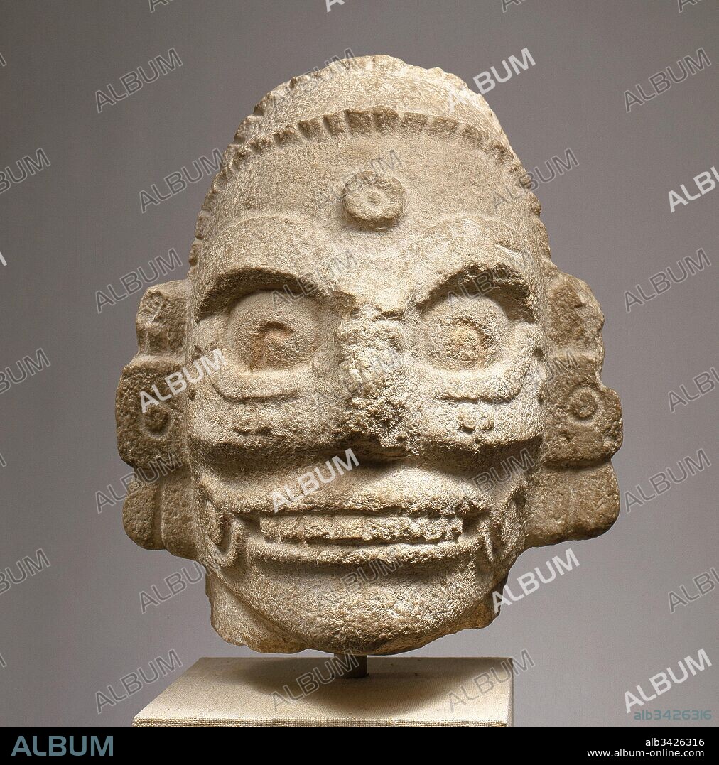 Head of a Rain God, 10th–11th century, Mexico, Mesoamerica, Yucatan, Maya, Fossiliferous limestone, H. 13 3/4 x W. 11 7/8 x D. 9 3/8 in. (34.9 x 30.2 x 23.8 cm), Stone-Sculpture, This monumental head carved from limestone depicts a supernatural being. Its subject is defined by skeletal features and wears large earflares and a beaded headband. Long hair is held back and indicated by deep incisions flowing down the reverse side of the head.