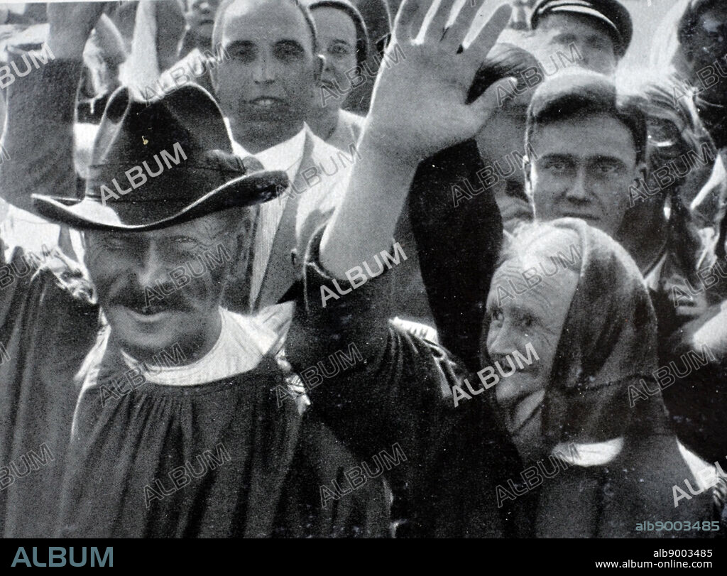 Nazi supporters gather to wave to Hitler as he passes through a town in Germany.