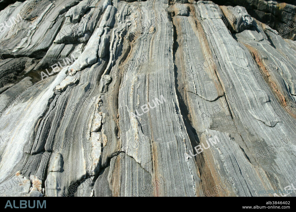 Close-up of granite with pink quartz inclusions. Granite is an igneous rock made from cooled magma. It consists of quartz, feldspars and usually also mica. It forms outcrops and highland areas; its hardness makes it difficult to erode.