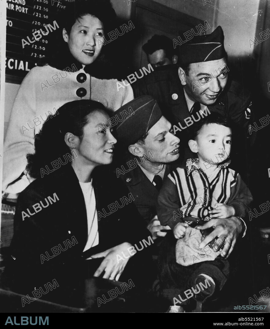 Korean War Brides -- Two Korean war brides get first view of U.S. surroundings shortly after arrival by Air Force plane here today Left to right, Sgt. Don Keller holding his son, Don, 20 months while wife, Chung, looks on. Sgt. First Class Adam Brychel and wife, Wha, Both are from Chicago, III. January 02, 1952.