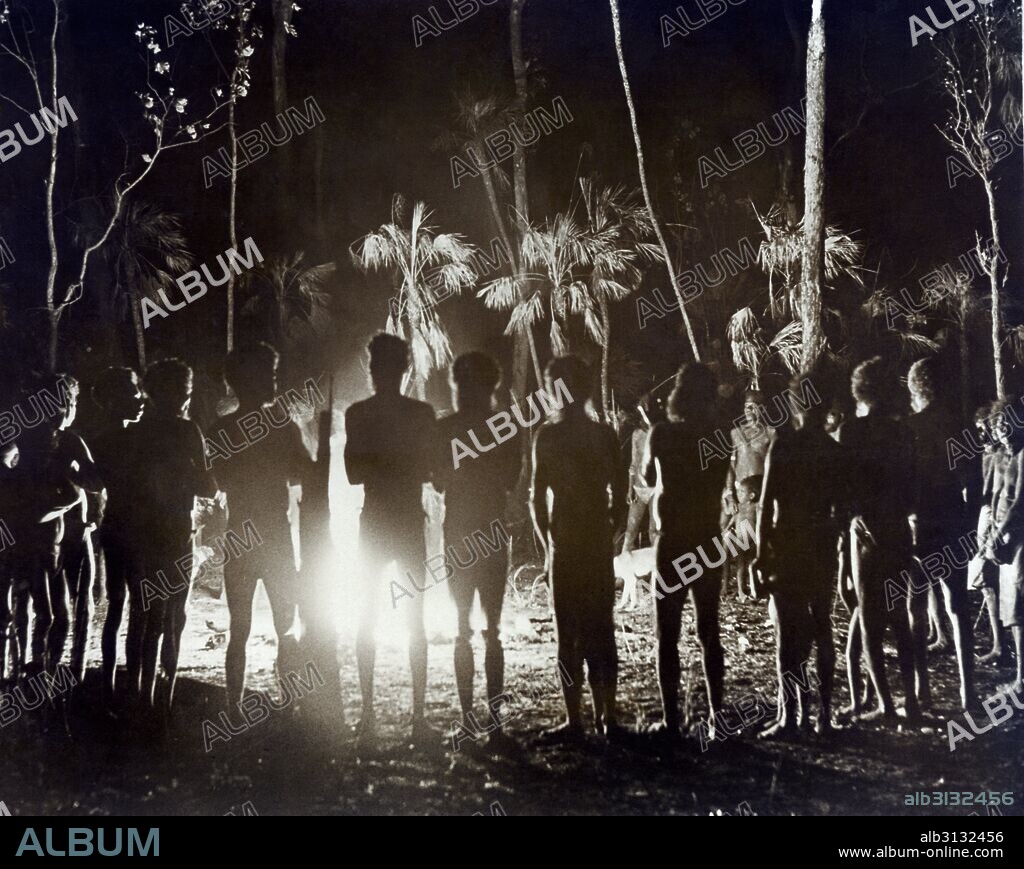 Australia:  c. 1935 Aborigines in Northern Australia gathered around a campfire during a corroboree or tribal gathering of a dreamtime spritual nature.