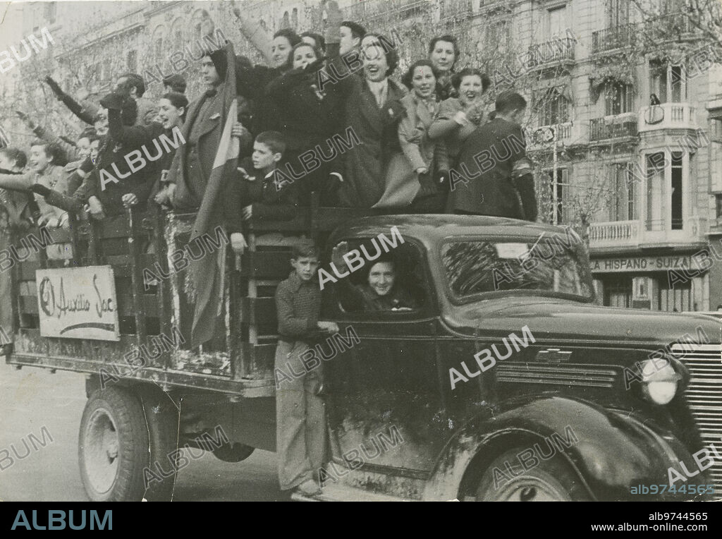 Barcelona, 26 de enero de 1939. Guerra Civil Española. En un camión de Auxilio social, un jubiloso grupo de barceloneses recorre las Ramblas. Después del largo paréntesis de los bombardeos, la entrada de las fuerzas nacionales en la capital catalana significaba poner fin a una larga y sangrienta guerra que estaba a punto de terminar.