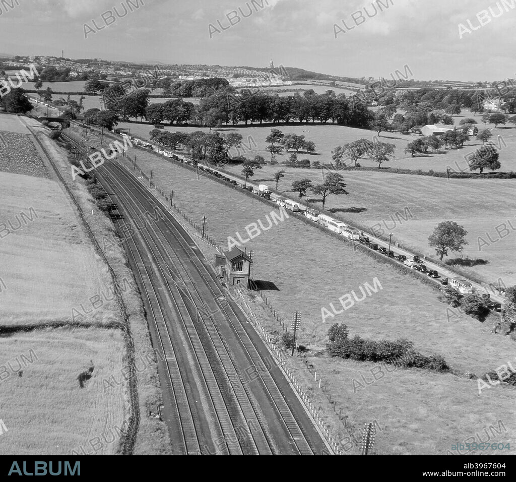 Traffic jam on the Preston-Lancaster Road, Lancashire, July 1951. A traffic jam of cars and coaches, on the road, while the adjacent railway lines are empty. From the Aerofilms Collection.