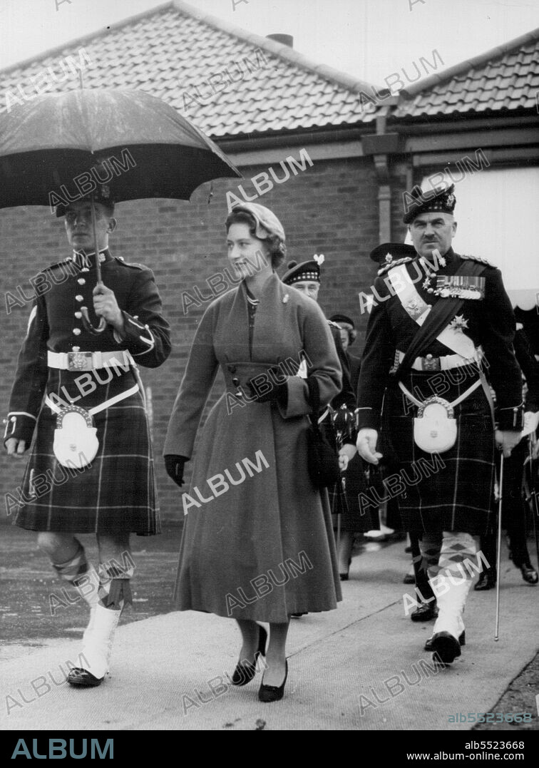 Princess Presents New Colours - The Princess, Colonel-In-Chief, is Sheltered by an Umbrella from the rain as she walks with the colonel, Major General R.E. Urquhart, during the ceremonies.Princess Margaret today October 19 presented New Colours to the 1st Battalion the Highland light infantry at Bulford Camp, Wiltshire. October 28, 1955. (Photo by Associated Press Photo).