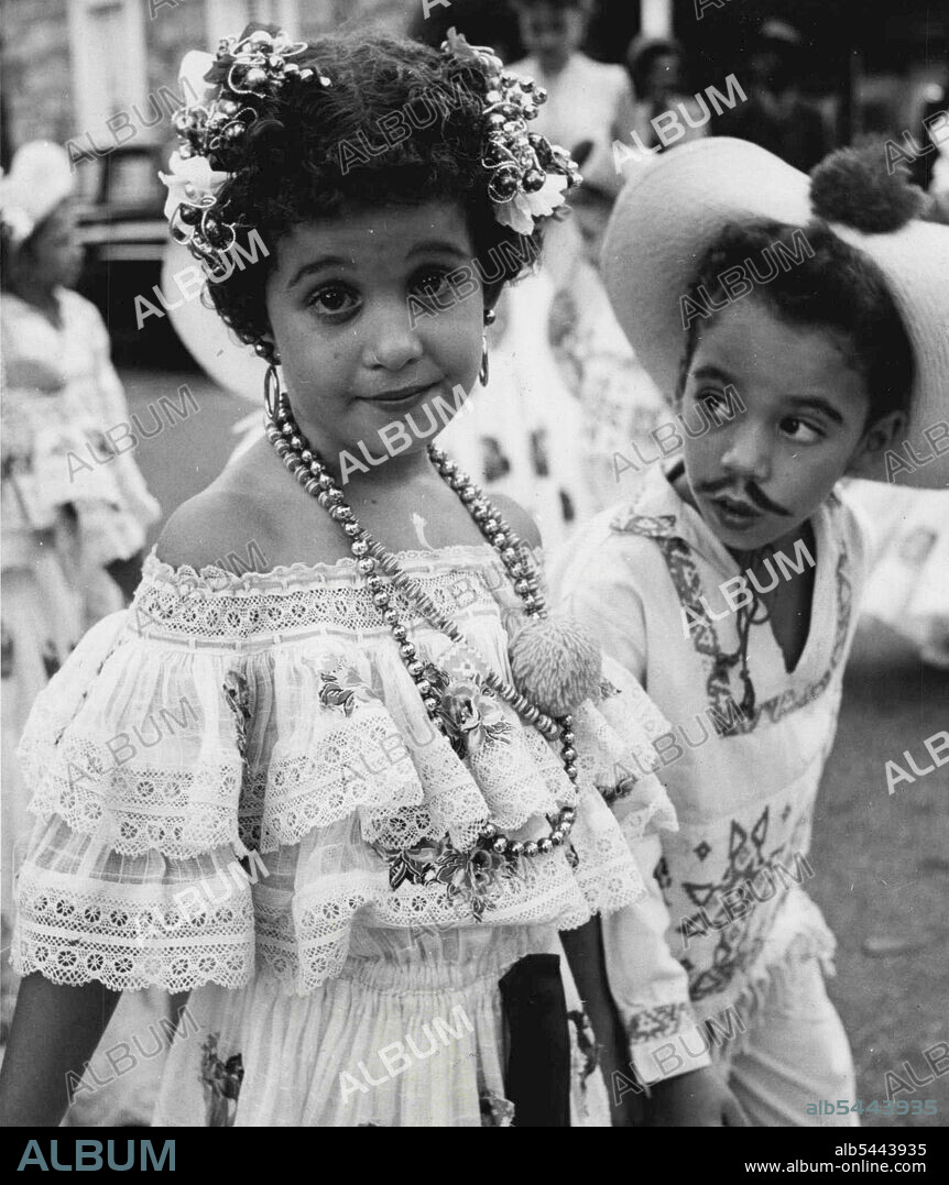 Gaily Dressed children welcome Princess Margaret on her tour of the Caribbean Calypso Islands. The little girl wore a lace dress, beads, hoop earrings - and tiny bells in her hair. Her escort wore an embroidered shirt and a painted-on moustache. February 22, 1955. (Photo by Daily Mirror).