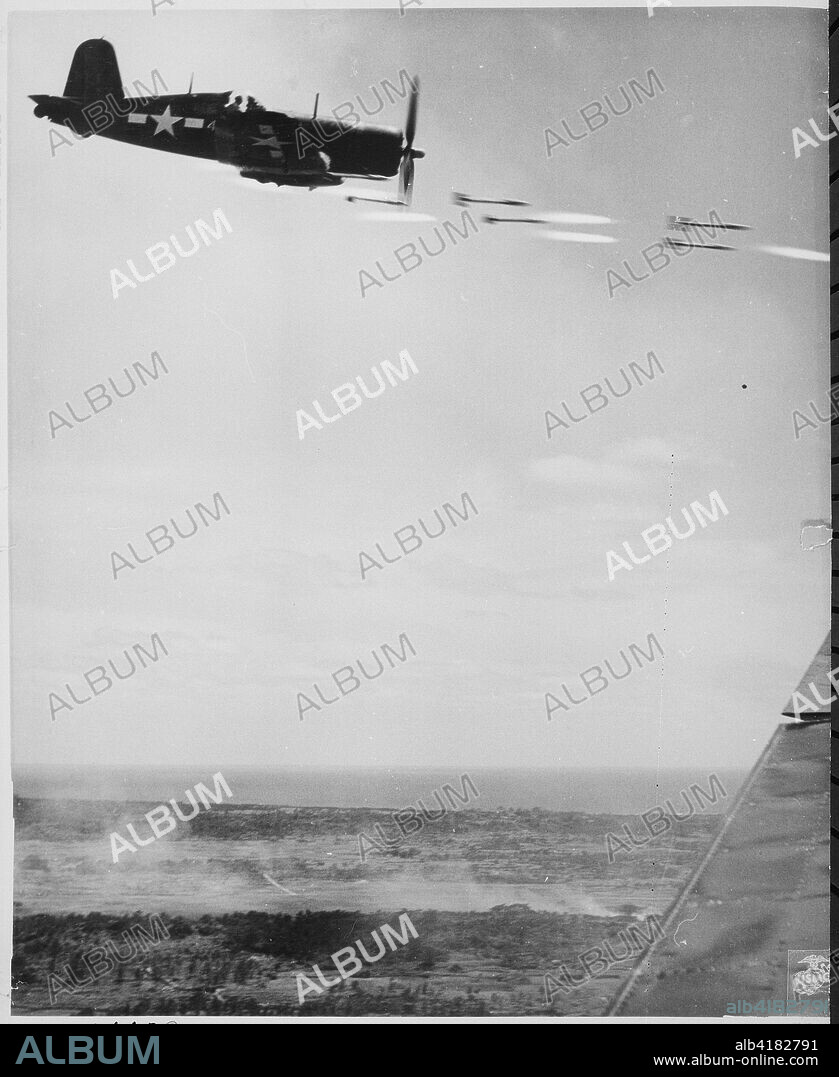 Corsair fighter looses its load of rocket projectiles on a run against a Japanese stronghold on Okinawa. In the lower background is the smoke of battle as Marine units move in to follow up with a Sunday punch. ca. June 1945.