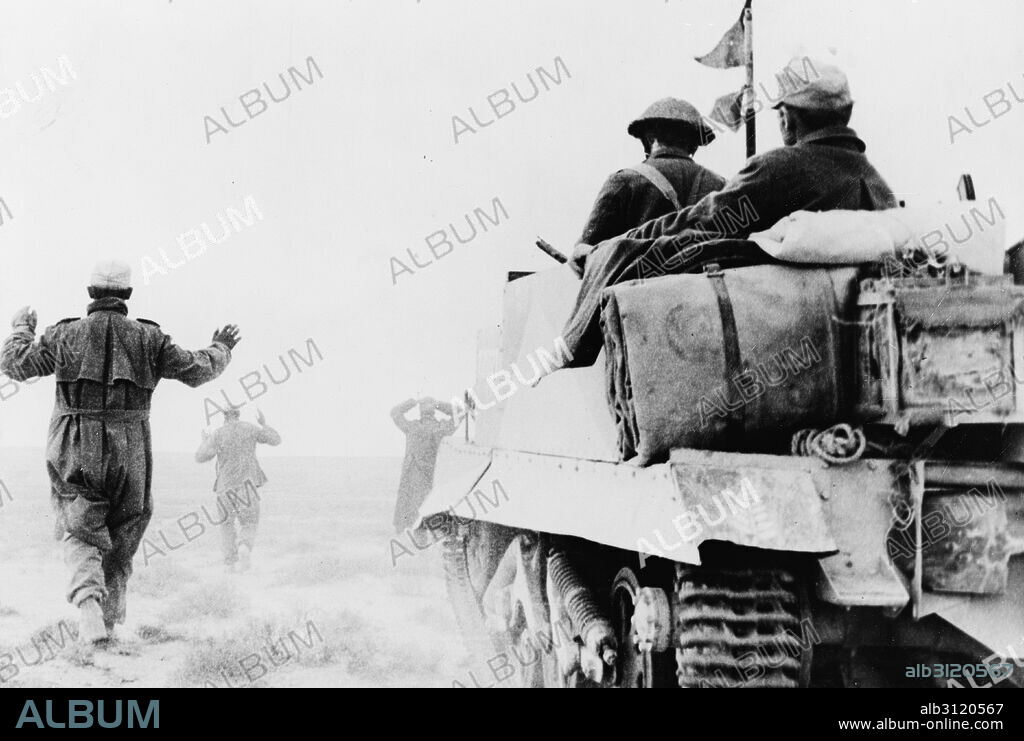 German infantry surrendering to men of New Zealand Bren carrier unit. A wounded prisoner can be seen riding in the back of the carrier, Jan, 1942.
