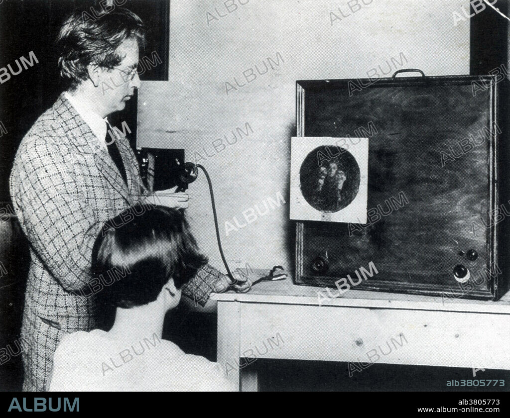 Editorial use only . Captioned: Baird demonstrating his television apparatus. (dated 1927) John Logie Baird (1888-1946) was a Scottish scientist, engineer, innovator and inventor of the world's first television. He built what was to become the world's first working television set using items including an old hatbox and a pair of scissors, some darning needles, a few bicycle light lenses, a used tea chest, sealing wax and glue. In 1925, he successfully transmitted the first television picture with a greyscale image: the head of a ventriloquist's dummy nicknamed Stooky Bill. He made many contributions to the field of electronic television after mechanical systems had taken a back seat. In 1939, he showed colour television using a cathode ray tube in front of which revolved a disc fitted with colour filters. In 1944, he gave the world's first demonstration of a fully electronic colour television display.
