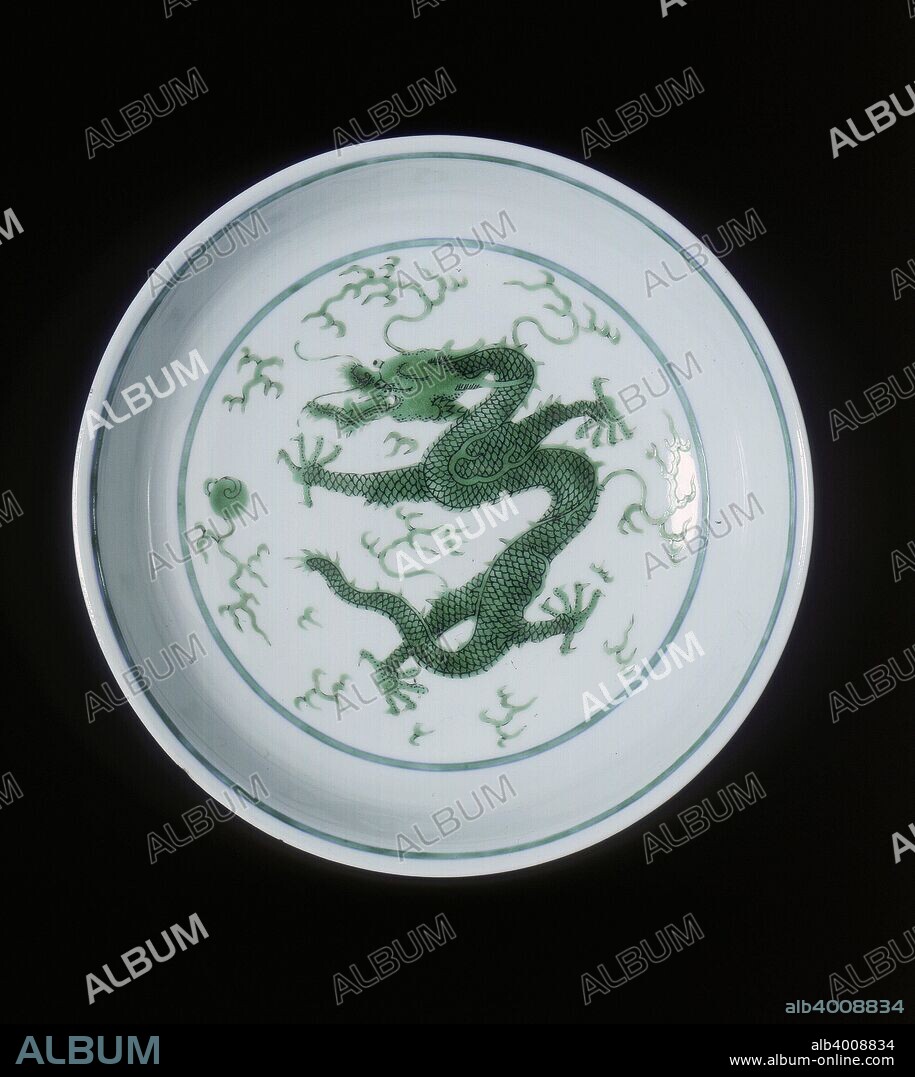 Green imperial dragon dish, Qianlong period, Qing dynasty, China, 1736-1795. A dish deocrated with a green five-clawed imperial dragon amid clouds chasing a flaming pearl. The reverse has two similar pearl-chasing dragons. There are green line borders and the background is plain without anhua waves. The base has an underglaze blue seal mark of Qianlong (without circle) surround and the piece is of the period.