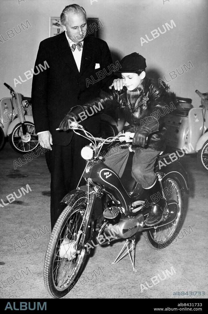 Orig.bildtext... Stockholmsskolornas motorexpert nr:1 är Lars Klintholm i sjuan i Adolf Fredriks folkskola. Lasse som fyller femton i år förklarades för vinnare i Wiklunds pristävling vad heter delen, alla skolgrabbars stora pyssel under senaste skollovet. Han klarade de tio frågorna om vad de olika delarna i en moped heter och fann dessutom det pigga slagordet Humlan är en finfin grej - passar mej, passer dej. -Studiochefen Tage Ericsson, ordförande i juryn, överlämnar här priset, en treväxlad DKW-Humlan av 1957 års modell. persons: Lars Klintholm ;Tage Ericsson sites: STOCKHOLM ;SVERIGE.