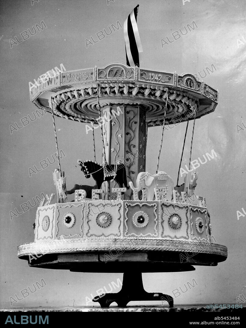 Winston's 'Merry-Go-Round' 75th Birthday Cake -- Place of honour on Mr. Winston Churchill's table to-morrow (Wednesday) will go to this ingenious and intricately-modelled cake, specially made by Mme. Floris of London for his 75th birthday.The Merry-go-Round cake, richly ornamented and decorated with gaily caparisoned horses and elephants, bears the unusual inscription: 'To Wish You a Happy Return'.Only inedible parts of the cake are Mr. Churchill's racing colours, gally floating above the merry-go-round.The firm, makers of the Churchill family birthday cakes for many years, were also responsible for Prince Charles' birthday cake. November 29, 1949. (Photo by Reuterphoto).