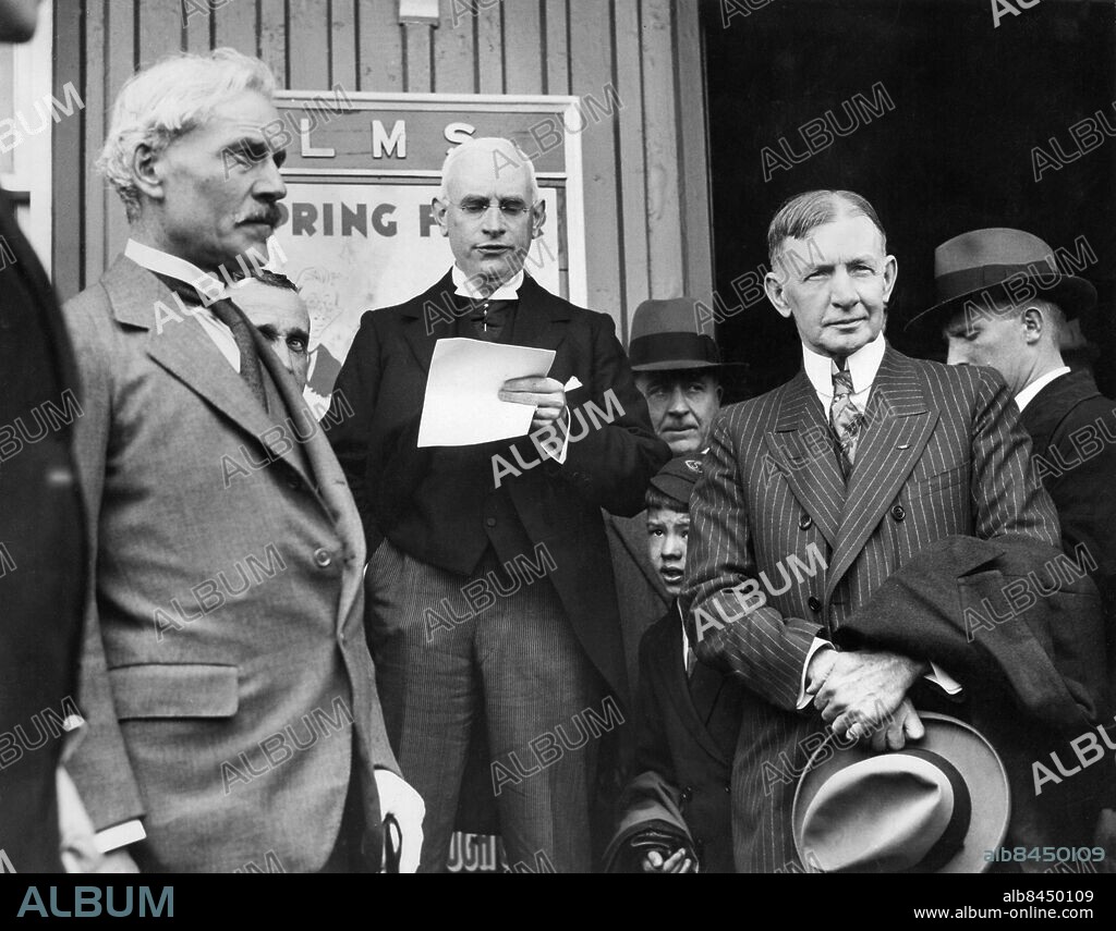 Orig. bildtext... GENERAL DAWES, NEW AMERICAN AMBASSADOR, HAS CONFERENCE WITH RAMSAY MACDONALD AT LOGIE HOUSE, NEAR FORRES, SCOTLAND. Photo shows: Ramsay MacDonald and General Dawes listening to the address of welcome on the General's arrival, being delivered by Bailee Caldwell. Anm. C G Dawes, 1865-1951, amerikansk ambassadör i Storbritannien. Nobels fredspris 1925 för återuppbyggnadsarbete efter första världskriget. R MacDonald, 1866-1937, brittisk premiärminister två gånger från 1924. Ambassadörer Talare Trio Manus Kepsar CD499 persons: CHARLES GATES DAWES;RAMSAY MACDONALD sites: USA*;STORBRITANNIEN;SKOTTLAND.